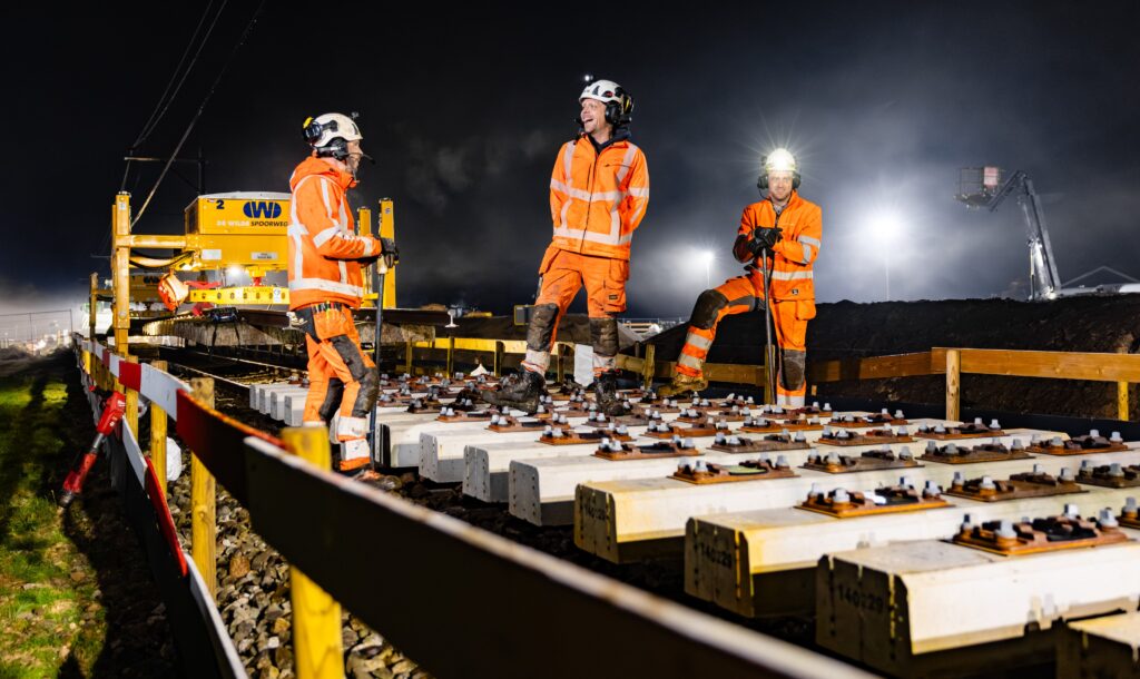 Monteurs van De Wilde Spoorwegbouw bij nachtelijk spoorwerk op nieuw gelegde betonnen dwarsliggers