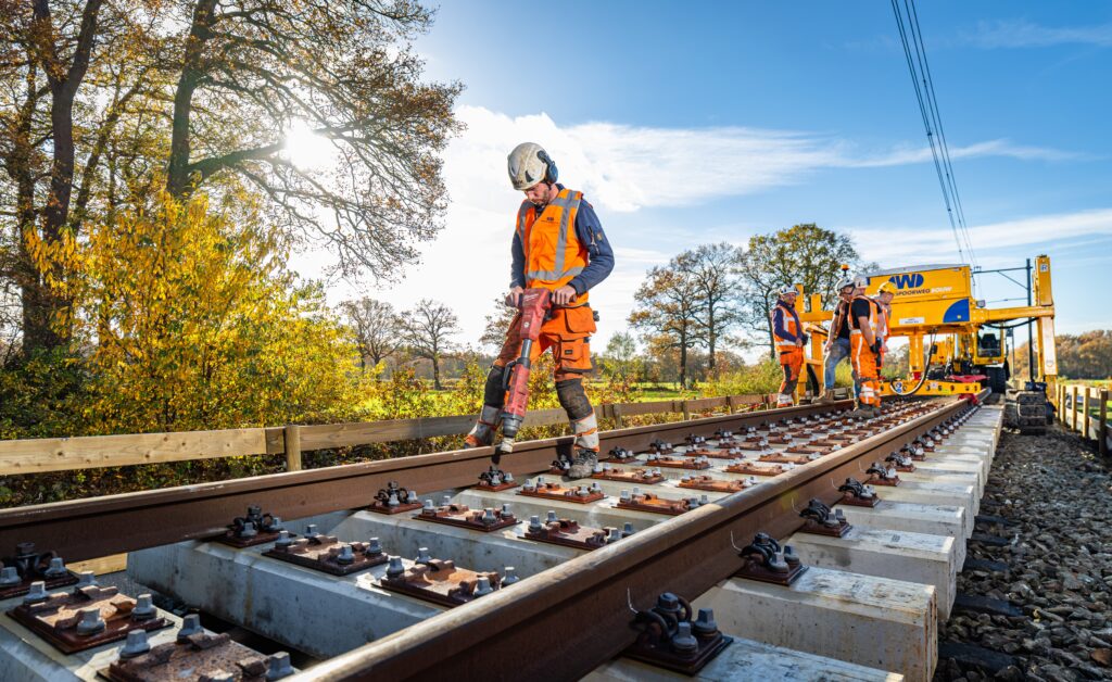 Monteur van De Wilde Spoorwegbouw zet bevestigingen vast op nieuw aangelegd spoor